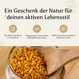 Nahaufnahme eines Glases mit goldgelbem Bienenbrot (Perga), in das eine Holzschaufel eingetaucht ist. Darüber ein Banner mit der Aufschrift 